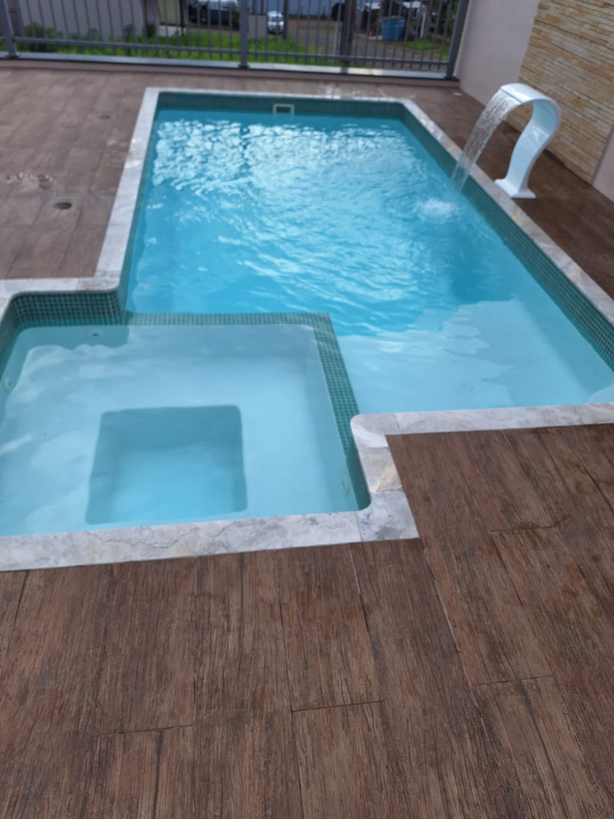 Piscina Jade com spa integrado e cascata em deck de madeira