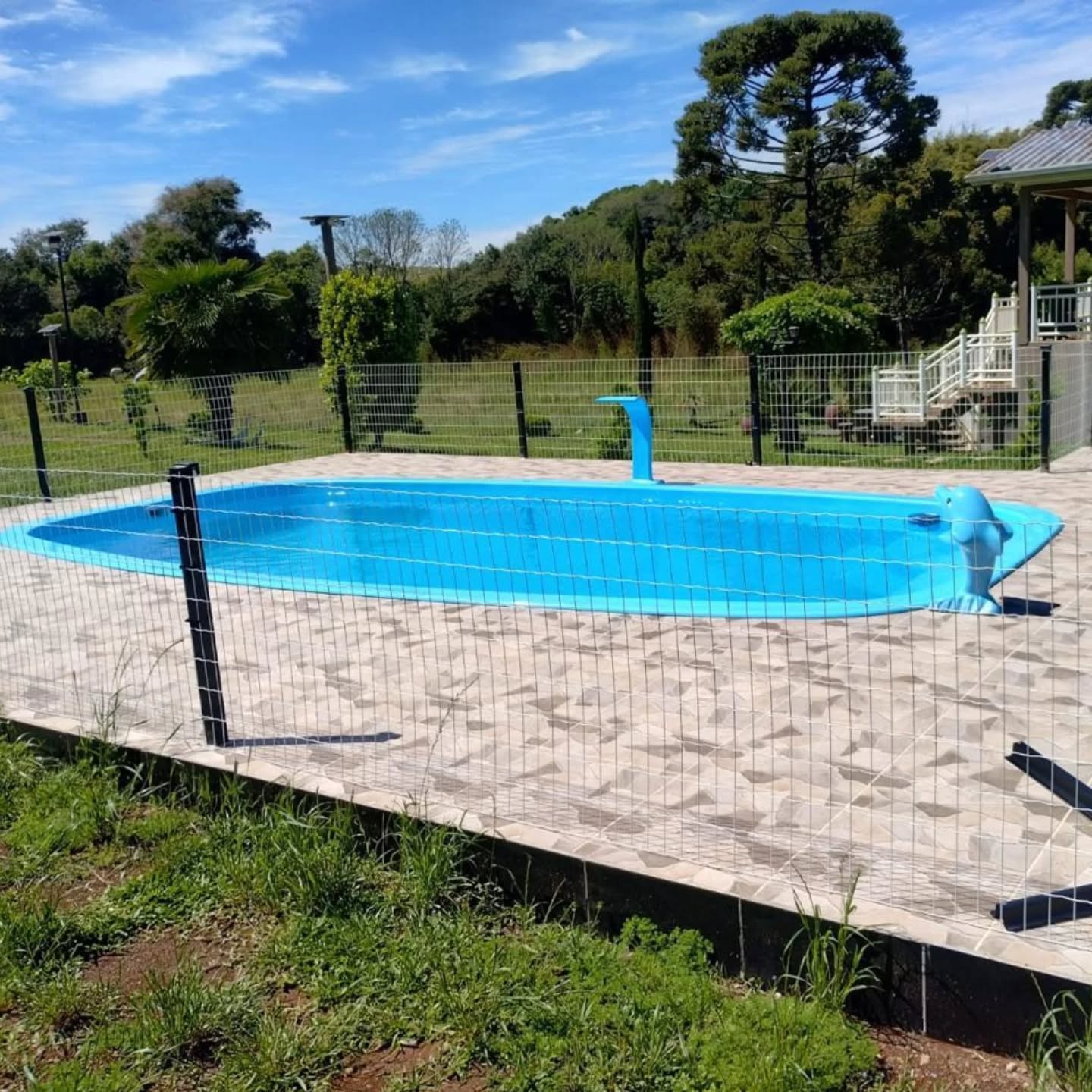 Piscina compacta com cascata em área externa cercada