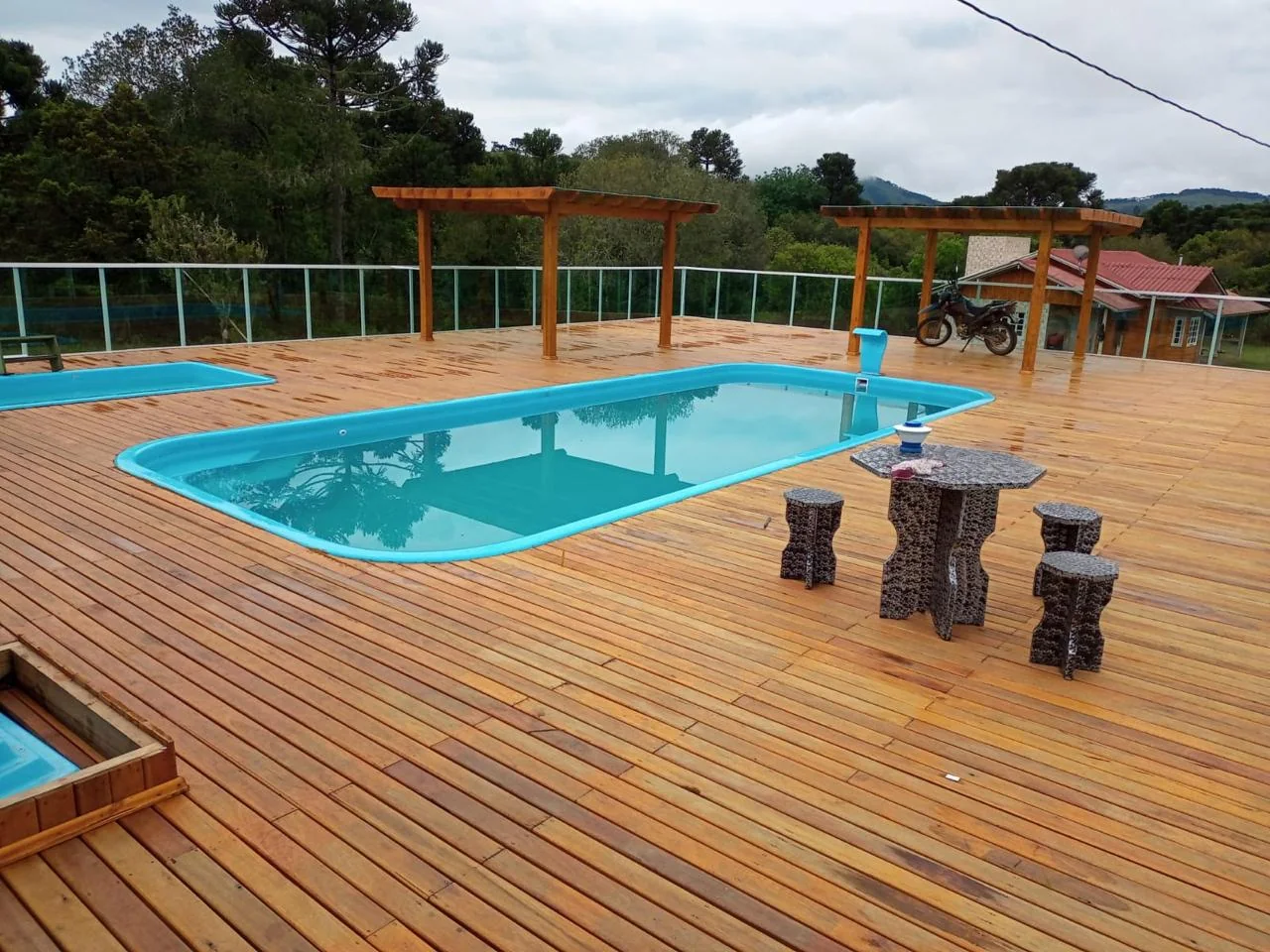 Piscina instalada pela UJR com amplo deck de madeira e pérgolas ao ar livre